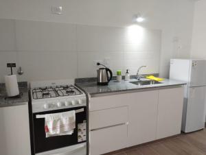a white kitchen with a stove and a refrigerator at Monoambiente a estrenar con Balcón in La Plata +2 photos