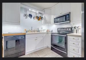 una cucina con mobili bianchi e un forno a piano cottura di Cape Canaveral Condo Steps from the Beach a Cape Canaveral