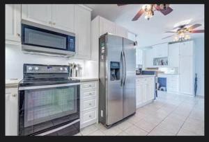 una cucina con frigorifero in acciaio inossidabile e mobili bianchi di Cape Canaveral Condo Steps from the Beach a Cape Canaveral