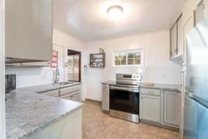 una cucina con armadi bianchi e un forno a piano cottura nero di Rockaway Beachhouse a Rockaway Beach