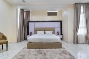 Un dormitorio con una gran cama blanca y una silla. en Aduni's Place, en Ikeja