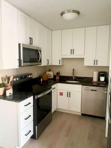 a kitchen with white cabinets and a black appliance at Coastal Countdown Relaxed Townhome Near Beach and Rockets in Cape Canaveral +3 photos
