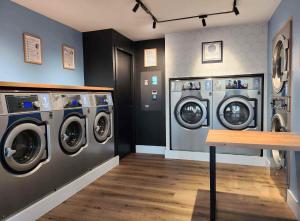 a laundry room with three washing machines and a counter at Aparthotel New Palmarium in Amélie-les-Bains-Palalda