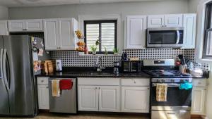 a kitchen with white cabinets and a stainless steel refrigerator at Vintage Home Vibe in Jersey City +8 photos