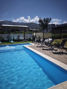 Una piscina azul con sillas y montañas al fondo. en Hermosas suites de lujo, en Tafí del Valle