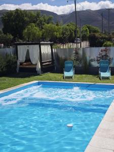 Dos sillas y una piscina en un patio. en Hermosas suites de lujo, en Tafí del Valle
