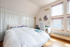 1 dormitorio con cama blanca, escritorio y ventanas en Sapporoの実家 B&B Yoshida, en Sapporo