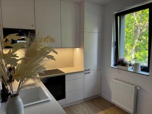 a kitchen with white cabinets and a window and a sink at Apartament Morzlive in Ustronie Morskie