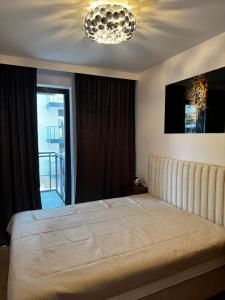 a bedroom with a large bed and a chandelier at Apartament Morzlive in Ustronie Morskie +14 photos