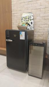 Un refrigerador negro al lado de una silla en una habitación. en Flat JK Luxo, en Ribeirão Preto