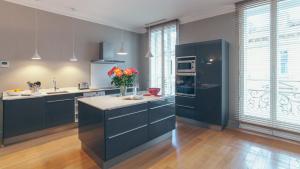 a kitchen with blue cabinets and a black refrigerator at Appartement T4 cours de l'intendance in Bordeaux