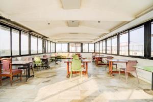 un comedor con mesas, sillas y ventanas en Collection O Infocity Metro Station Gandhinagar Formerly Hotel LLP, en Gandhinagar 29 fotos más