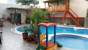 a swimming pool with a slide in front of a house at Hotel Arena Caliente in Playas +2 photos