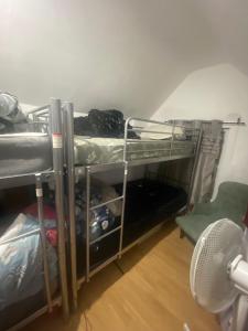 a room with two bunk beds and a fan at Cheapest Sharing Room Dagenham East Station in Dagenham