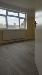 an empty room with a cross on the wall and two windows at Cheapest Sharing Room Dagenham East Station in Dagenham