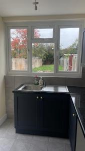 a kitchen with a sink and two windows at Cheapest Sharing Room Dagenham East Station in Dagenham