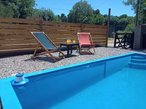 two chairs and a table next to a swimming pool at Tranqueras al Norte in Chascomús