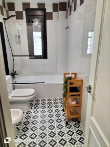 a bathroom with a white toilet and a black and white tile floor at Casa Palacio Arcos del Carmen in Jerez de la Frontera