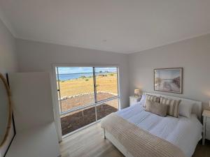 Pelican Lagoon Retreat في Pelican Lagoon: غرفة نوم مع سرير وإطلالة على المحيط