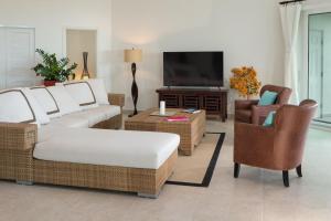 a living room with a couch and chairs and a television at Karana 4 Bedroom in Long Bay Hills