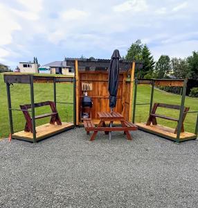 two picnic tables and benches in front of a building at Flying Plate Saloon in Waimate +2 photos