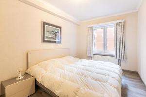 een slaapkamer met een wit bed en een raam bij Sun Beach 0201 in Sint-Idesbald