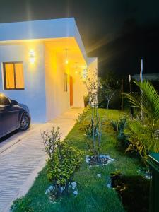 蓬塔卡纳Habitación en Casa Familiar con Baño Privado en Punta Cana的一座有植物和汽车的院子的房子