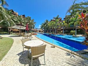 Parque das Ilhas • Resort Perto do Beach Park في Mangabeira: طاولة وكراسي بجانب مسبح