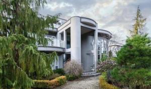 ein großes weißes Haus mit einem Balkon und Bäumen in der Unterkunft Vancouver Airport Blueberry Manor in Richmond