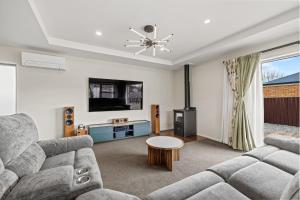 a living room with a couch and a tv at City Fringe-Guest House in Christchurch