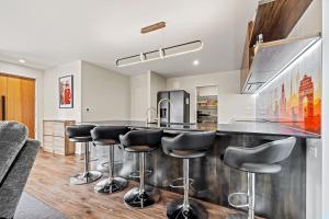 a kitchen with a bar with black stools at City Fringe-Guest House in Christchurch