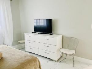a bedroom with a tv on a dresser with a chair at Stylish 1BR 2BA Condo 1Block to Aventura Mall in Aventura