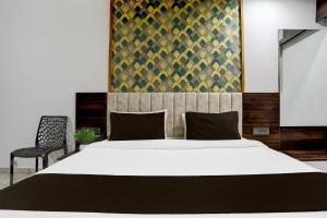 アーメダバードにあるSuper Hotel O Nana Chiloda Near Airport Formerly Green Valleyの大きな白いベッドと椅子のある寝室