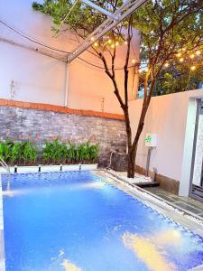 a pool with blue water and a tree in front of a building at Solia Villa in Da Nang