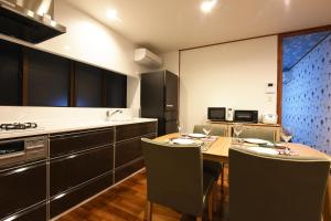 eine Küche mit einem Tisch mit Stühlen und einem Herd in der Unterkunft 読谷ORENCHi in Yomitan