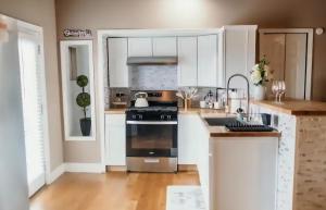 a kitchen with white cabinets and a stove top oven at Couples Guesthouse, jacuzzi, sauna, pool in Merrillville
