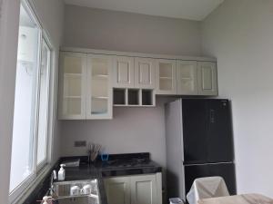 a kitchen with white cabinets and a black refrigerator at Rumah Cluster Springwood1 in Pontianak