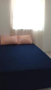a blue bed with a pillow and a window at Recanto Santa Lídia in Penha