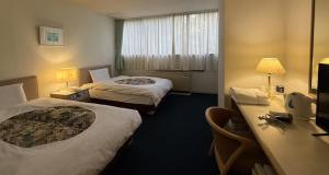 una camera d'albergo con due letti e una scrivania di VoyStay Fuji a Fujinomiya