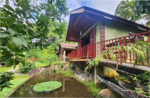 Teratak Jannah Homestay & Resort في كوالا لكانغسار: منزل به جسر فوق بركة في حديقة