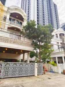 a white house with a tree in front of some buildings at Danita's Home Bangkok in Bangkok +23 photos