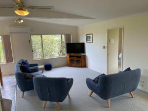 a living room with blue chairs and a flat screen tv at Beach Dreaming - coastal retreat walk to beach in Mollymook