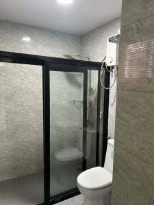a bathroom with a toilet and a glass shower at Cozy Baguio House Near Camp John Hay in Baguio