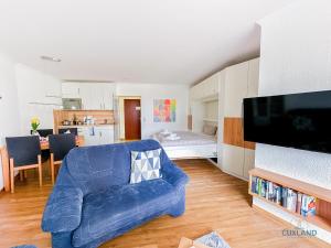 a living room with a blue couch and a kitchen at Lord Nelson Wohnung 118 in Döse