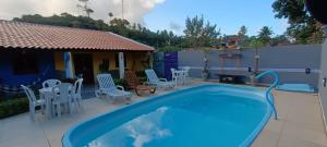 Una gran piscina con sillas y una mesa. en Chalé Aconchego dos Milagres, en São Miguel dos Milagres