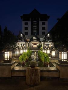 ein Gebäude mit Lichtern und einem Brunnen davor in der Unterkunft Wienglakor Hotel Lampang in Lampang
