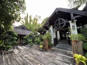 ein Haus mit einer Holzterrasse mit Pflanzen darauf in der Unterkunft Wienglakor Hotel Lampang in Lampang