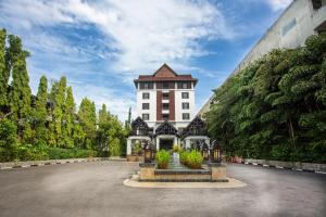 ein großes weißes Gebäude mit einem Uhrenturm in der Unterkunft Wienglakor Hotel Lampang in Lampang