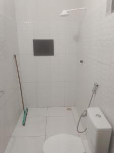 a white tiled bathroom with a toilet and a broom at Cantinho da Rosa in Santo Amaro