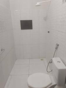 a white bathroom with a toilet and a window at Cantinho da Rosa in Santo Amaro